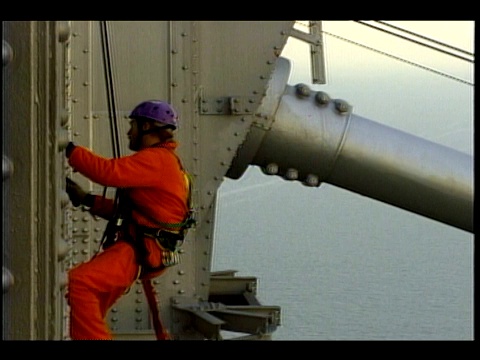 旧金山海湾大桥上，一名维修工人吊在吊带上。视频下载