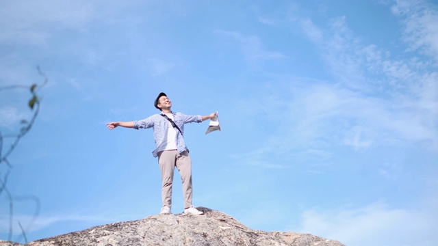 亚洲男人举起双手，与蓝天和顶山景，生活理念。缓慢的运动。视频下载