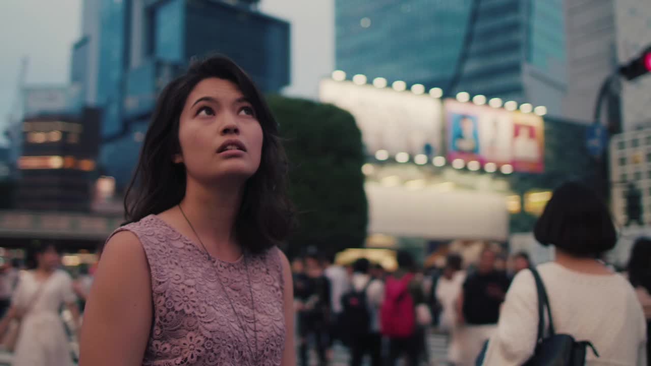 日本一名女子站在繁忙的十字路口，抬头仰望/东京，日本视频下载
