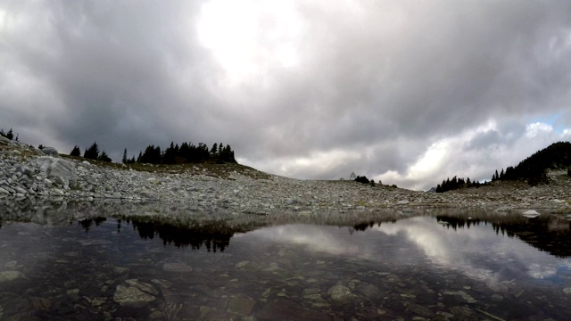 时间流逝，一个平静的湖在山与云在天空视频素材