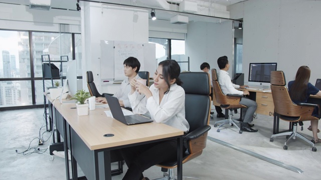 4K超高清:亚洲女员工在现代办公背景下使用笔记本电脑工作。视频下载