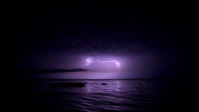 闪电在暗紫色的天空中闪烁。视频下载