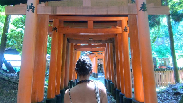 一个女人独自走在日本牌坊走廊上，稳步拍摄视频下载