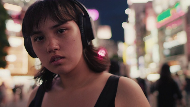 日本东京，一个晚上戴着耳机的年轻日本女人的肖像视频素材