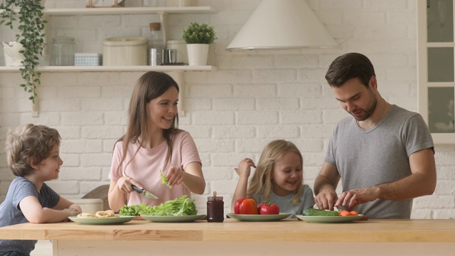 快乐的父母和孩子们一起在厨房切沙拉视频素材