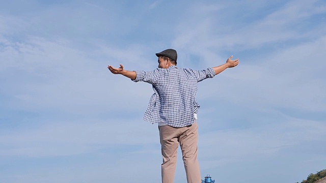 亚洲男人举起双手，与蓝天和顶山景，生活理念。缓慢的运动。视频下载
