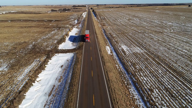 汽车行驶在乡村农田中收获的田地之间的小公路上的风景全景鸟瞰图视频下载