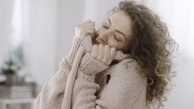害羞的女人把脸藏在针织毛衣里视频下载