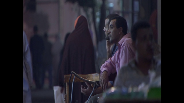 两名埃及男子一边看着过往的行人一边交谈。视频下载