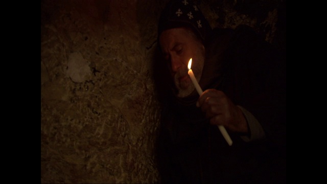 一个穿长袍的埃及人拿着一支蜡烛穿过一个洞穴。视频下载