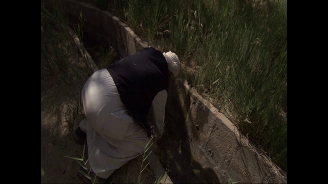 一名戴着头巾的埃及男子正在用手清理灌溉渠。视频下载