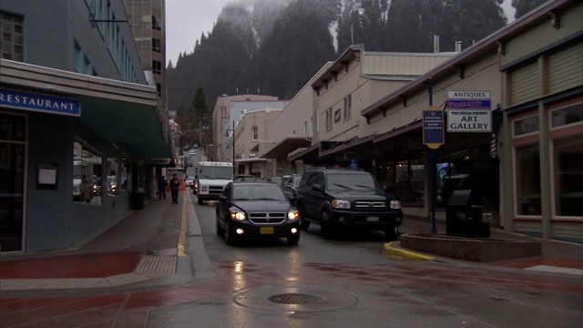 在阿拉斯加州朱诺市，一辆汽车和一辆邮车在被雨淋湿的街道上行驶。视频下载