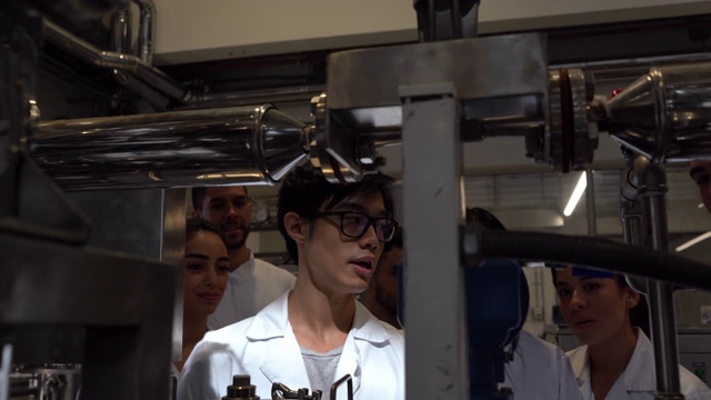 亚洲化学学生解释蒸馏过程如何在大学实验室工作视频素材