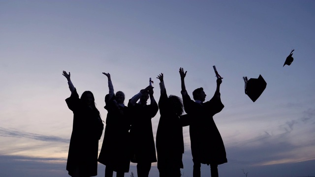 庆祝毕业的国际学生剪影，向空中抛帽子视频下载