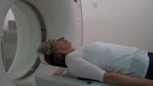 一位年长的妇女躺在平板扫描仪上准备进行脑部核磁共振扫描视频下载
