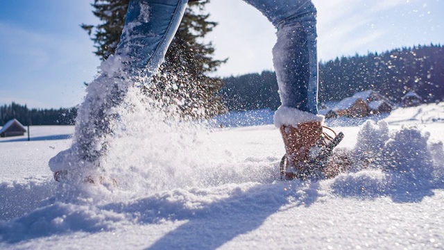 脚上绑着雪鞋在刚落下的粉末雪地上徒步旅行视频素材