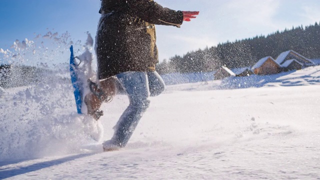 脚上绑着雪鞋在刚落下的粉末雪地上奔跑视频素材