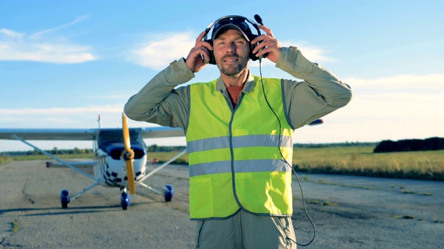 男性飞行员戴着耳机站在机场，特写。视频素材
