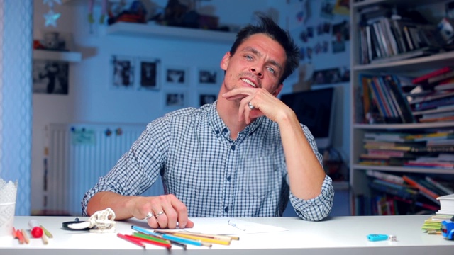 一个蓝眼睛的男人坐在桌子前摆姿势视频素材