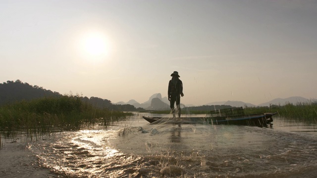 日落时分，渔民在湖边用小船撒网。渔民的生活方式。泰国华富里以。视频素材