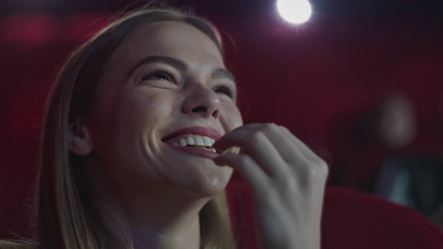 微笑的女人在电影院吃爆米花视频下载