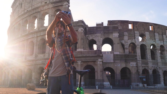 快乐的年轻游客穿着衬衫和帽子在罗马斗牛场拍摄照片，意大利，日出。视频下载