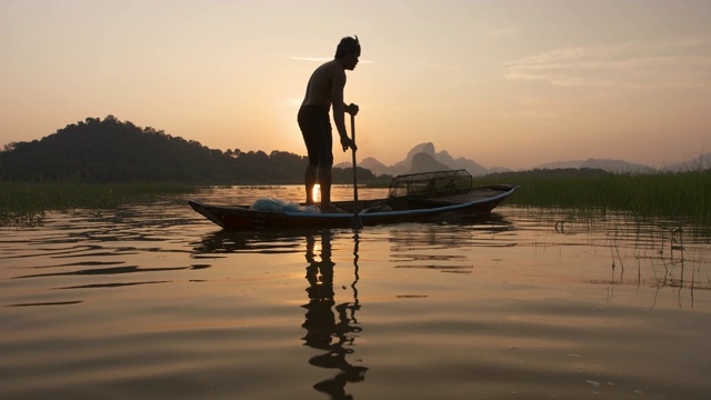 傍晚时分，渔民们在湖面上划着木船准备垂钓。渔民的生活方式。泰国华富里以。视频素材