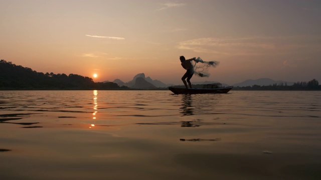 日落时分，渔民在湖边用小船撒网。渔民的生活方式。泰国华富里以、亚洲。视频素材