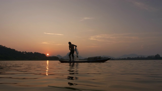 日落时分，渔民在湖边用小船撒网。渔民的生活方式。泰国华富里以、亚洲。视频素材