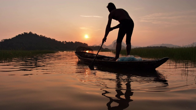 傍晚时分，渔民们在湖面上划着木船准备垂钓。渔民的生活方式。泰国华富里以、亚洲。慢动作视频下载