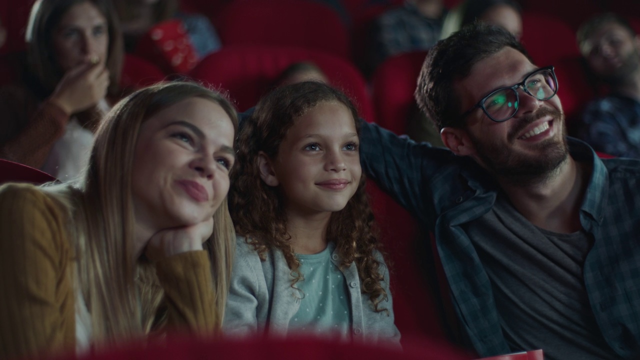 年轻微笑的家庭带着孩子在电影院视频下载