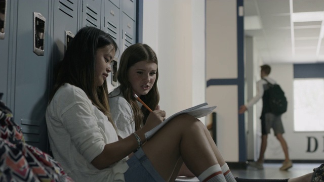 低角度的女孩说话和靠在学校走廊的储物柜/普罗沃，犹他州，美国视频素材