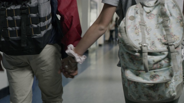 男孩和女孩手牵着手走在学校走廊的近距离跟踪镜头/普罗沃，犹他州，美国视频下载