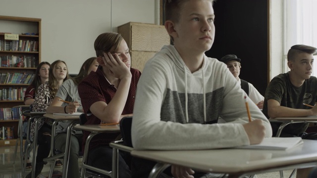 放大图片:美国犹他州普罗沃，一个无聊的男孩在学校教室里用手托着下巴视频下载