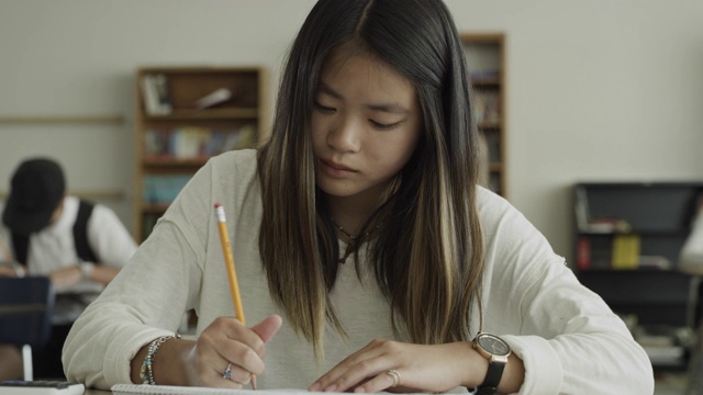 慢镜头拍摄的女孩写在笔记本在学校教室/普罗沃，犹他州，美国视频素材