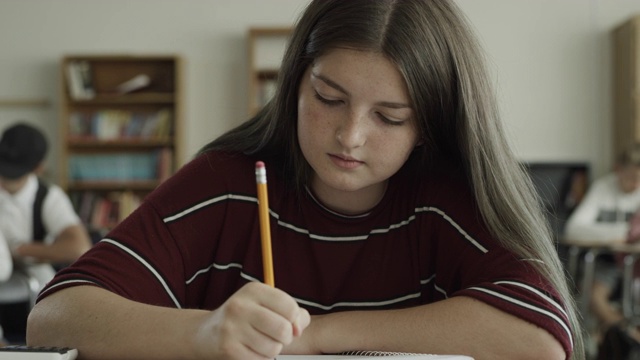 慢镜头拍摄的女孩写在笔记本在学校教室/普罗沃，犹他州，美国视频素材