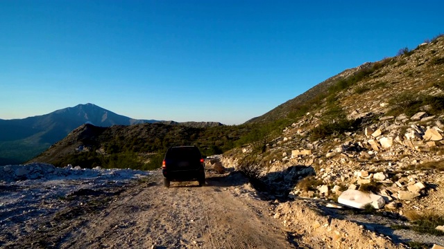 越野车越野车4x4驾驶下坡在危险的乡村道路在山区，电影定速镜头视频素材