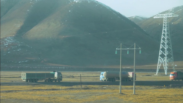 慢镜头:大型卡车在西藏平原上会合，运送货物。视频购买