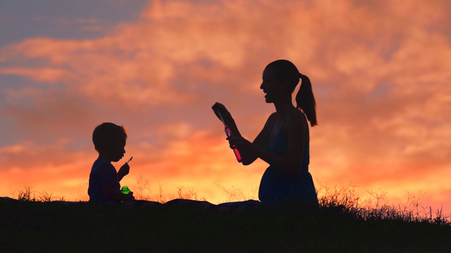 日落时分，快乐的母子在公园里吹泡泡视频素材