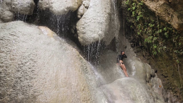 在夏天的热带瀑布下淋浴的亚洲妇女。视频素材
