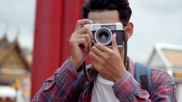 英俊的年轻亚洲男子的肖像独自游客在泰国的巨大秋千拍照。亚洲男子博客愉快享受休闲生活方式旅游。视频素材
