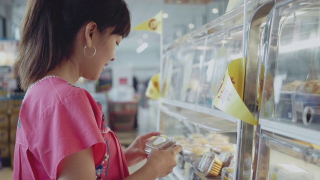 年轻的亚洲妇女在咖啡店选择蛋糕视频素材