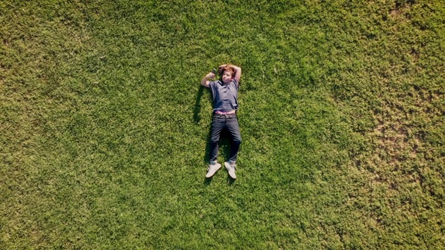 十几岁的男孩躺在草地上玩他的智能手机视频素材