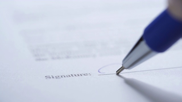 商人签署商务合同协议，男性的手特写用钢笔在商务表格上书写签名视频素材