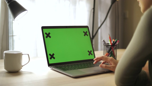 近距离女人使用色度键屏幕笔记本电脑在家里的桌子上视频下载