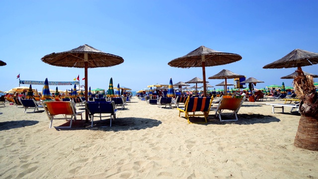 夏日海滩度假酒吧休息区与木制舒适椅子和稻草阳伞排在旁边的海水视频素材
