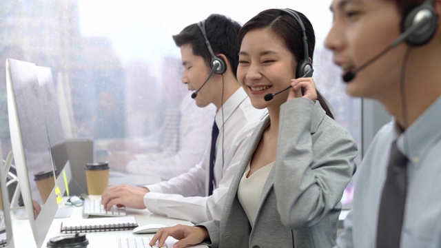 微笑的亚洲女性呼叫中心接线员与电话营销团队视频素材