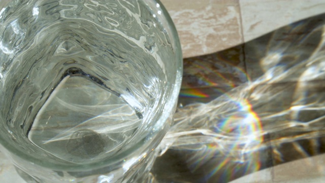 用透明的玻璃杯喝水。太阳眩光视频素材