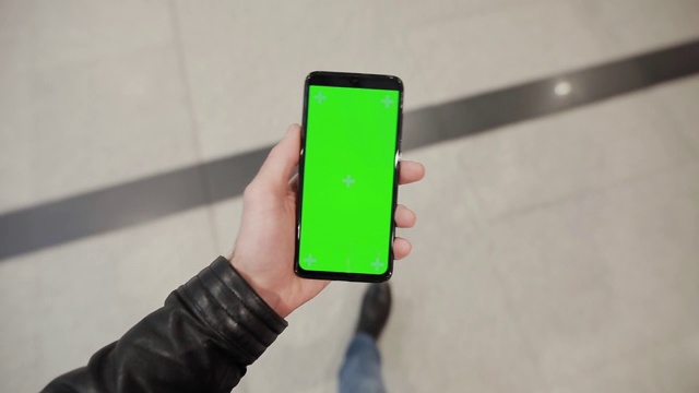POV，男性手拿绿屏智能手机走在商场里视频素材