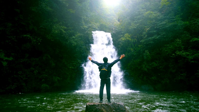 自由旅行，人站在瀑布前举起手臂视频下载